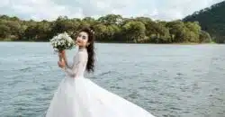 woman holding bouquet of flowers wearing wedding dress standing on dock during day