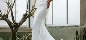 woman in white wedding dress standing beside green plant