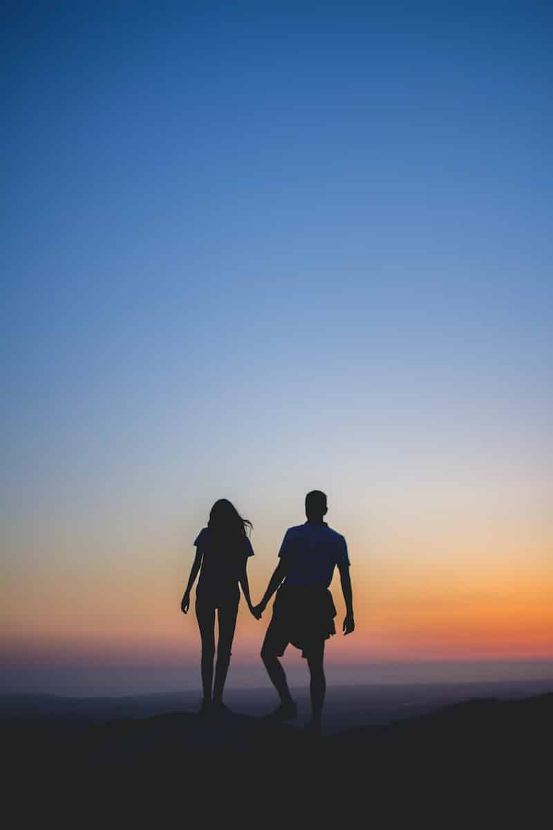 man and woman holding hands in silhouette photography